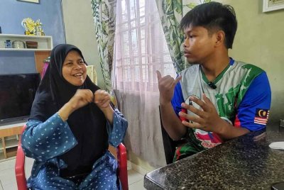 Muhammad Nabil (kanan) berkomunikasi dengan ibunya menggunakan bahasa isyarat.