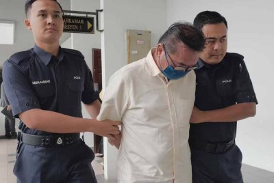 Tuan Hai (tengah) ketika dibawa keluar dari Mahkamah Sesyen Melaka pada Isnin.