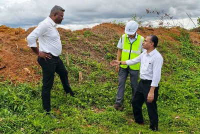 Arul Kumar (kiri) melihat penanda kawasan laluan paip gas di sebuah tapak projek di Sendayan.