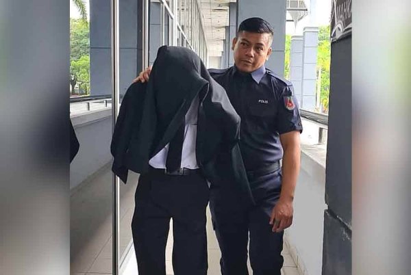 Abdul Hafiz (kiri) diiring polis ketika hadir ke mahkamah pada Isnin.