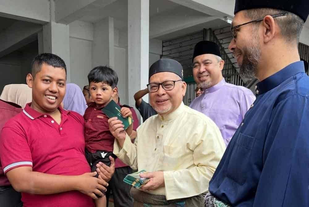 Mohd Amar (dua dari kanan) menyampaikan duit raya kepada kanak-kanak yang hadir.