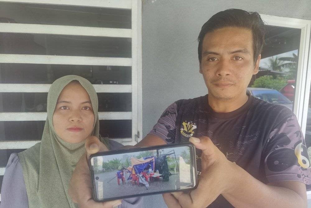 Shahrul Nazrin dan isterinya menunjukkan keadaan khemah niaga mereka yang rosak teruk akibat dibadai angin kuat dalam kejadian di Parit 4 Ban 2, Sekinchan pada Selasa.