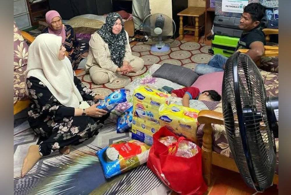 Juwairiya (kiri) melawat keluarga mangsa kebakaran di Kampung Kemensah, Hulu Kelang.