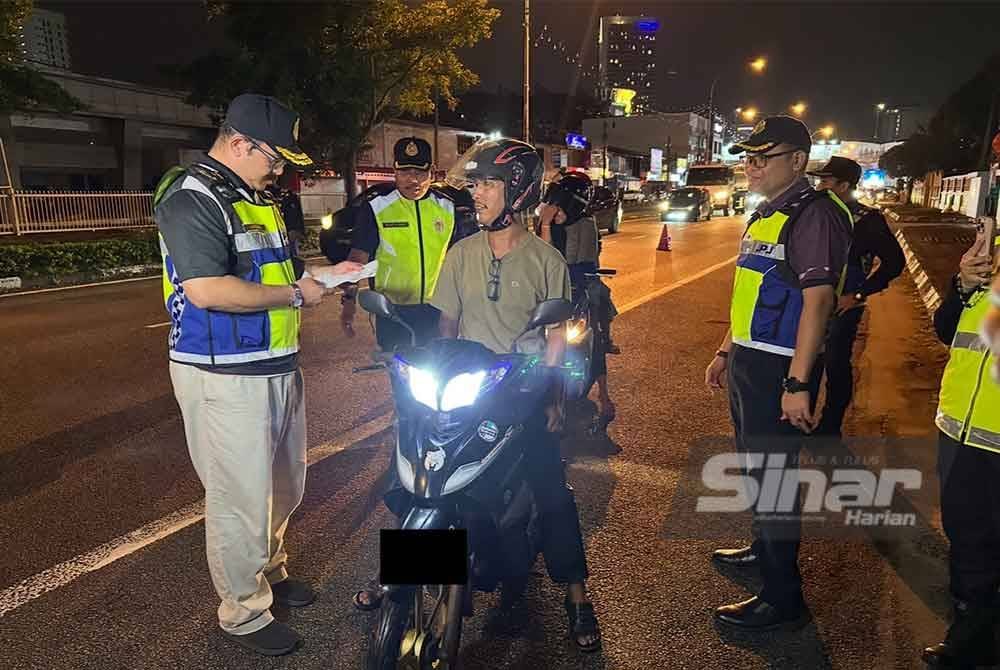 Mohd Misuari (kiri) melakukan pemeriksaan ke atas penunggang motosikal. FOTO SINAR HARIAN-ADILA SHARINNI WAHID