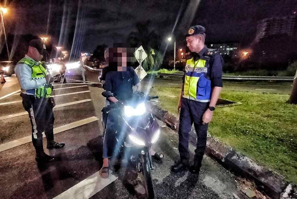 Khairul Aswad (kanan) bersama anggota polis memeriksa salah seorang penunggang motosikal dalam operasi itu