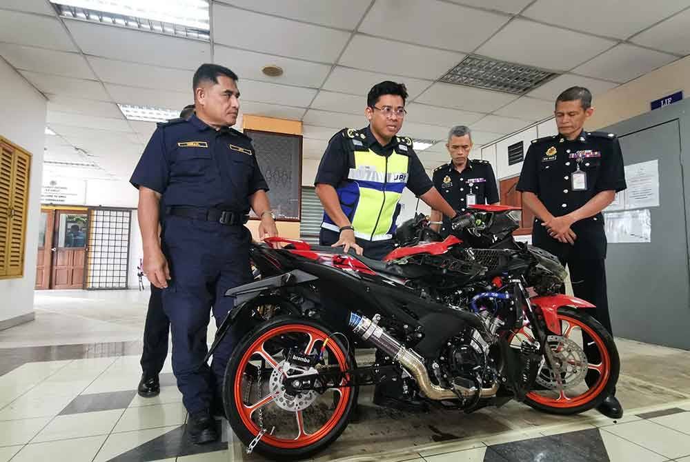 Mohd Zamri (dua dari kiri) menunjukkan motosikal yang ditahan selepas merempuh SJR pada malam Selasa.