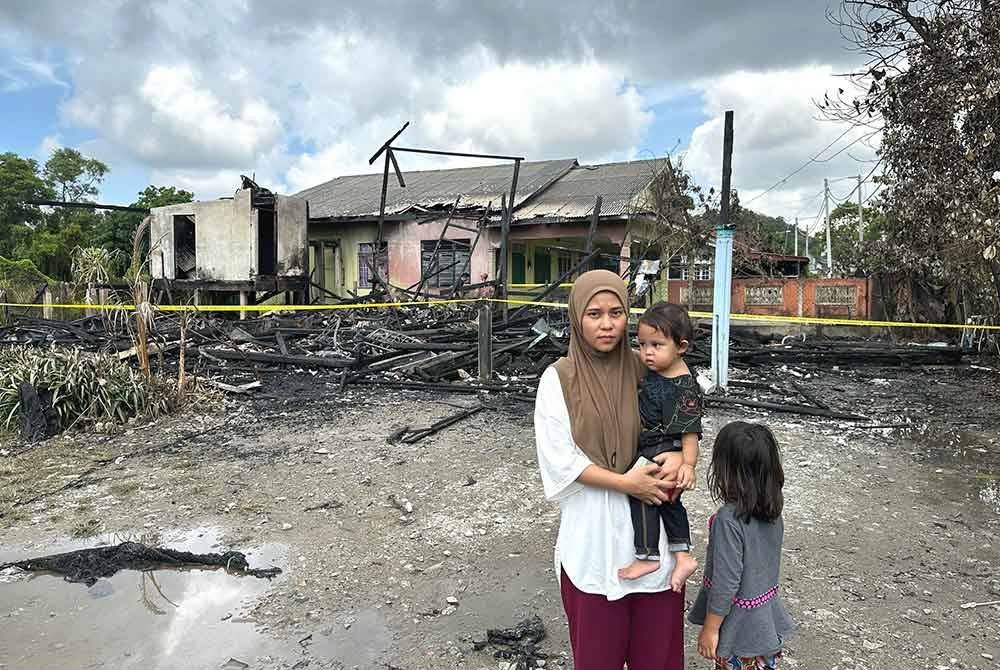 Nurul Waddah bersama dua anaknya melihat keadaan rumah yang terbakar dalam kejadian di Kampung Gelong Gajah, di Kuala Terengganu pada malam Selasa.