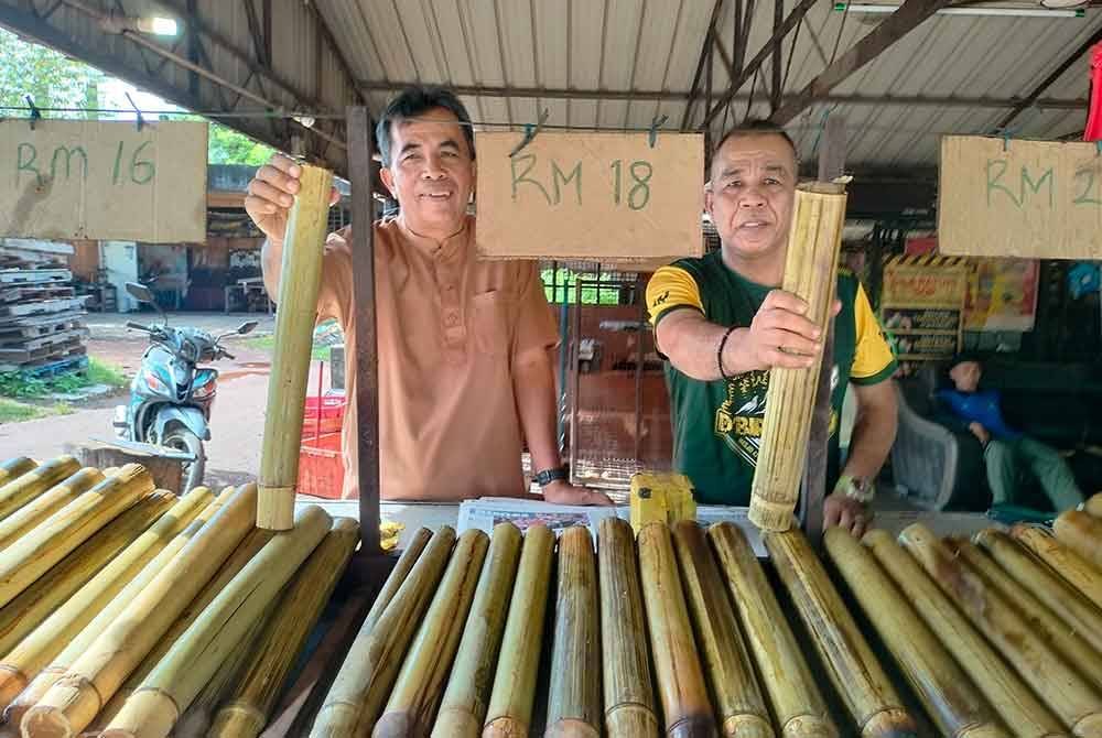 Azizan (kiri) masih mengekalkan harga lemang seperti lima tahun lalu.