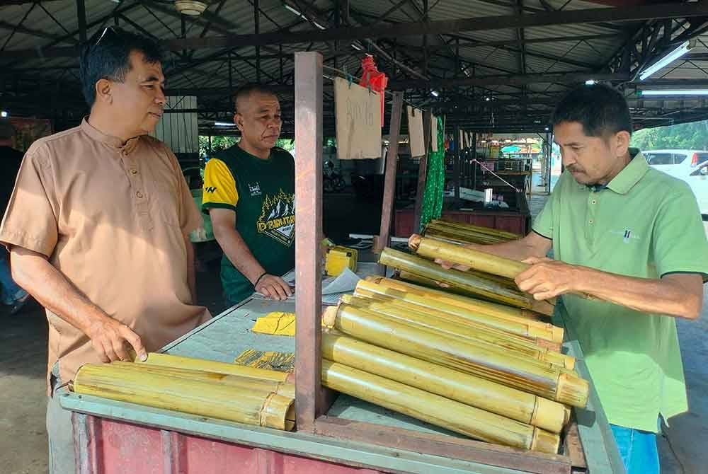 Azizan (kiri) melayan pelanggan di gerai Lemang Pakteh dekat Taman Rhu Sungai Petani.