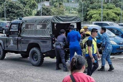 Pihak berkuasa membantu mengusung mayat mangsa ke dalam kenderaan polis.