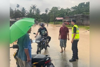 Anggota Polis sedang meninjau kawasan yang dilanda banjir kilat dan bertanyakan khabar pada penduduk.