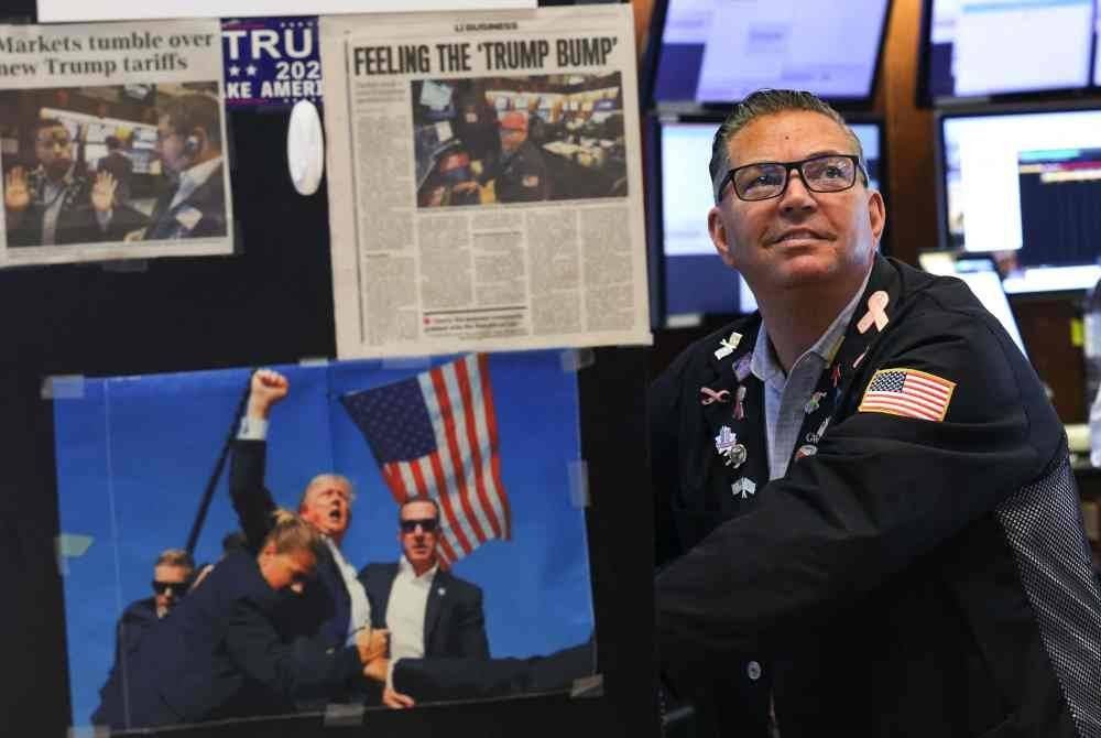 Keratan akhbar dan imej Presiden Amerika Syarikat Donald Trump dipamerkan ketika para pedagang bekerja di Bursa Saham New York (NYSE) semasa loceng pembukaan pada 9 April 2025, di New York City. - Foto AFP