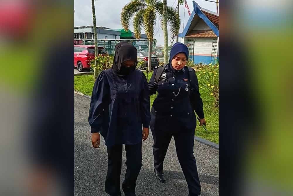Tertuduh (kiri) diiringi polis tiba di Mahkamah Majistret Sungai Besar pada Khamis.