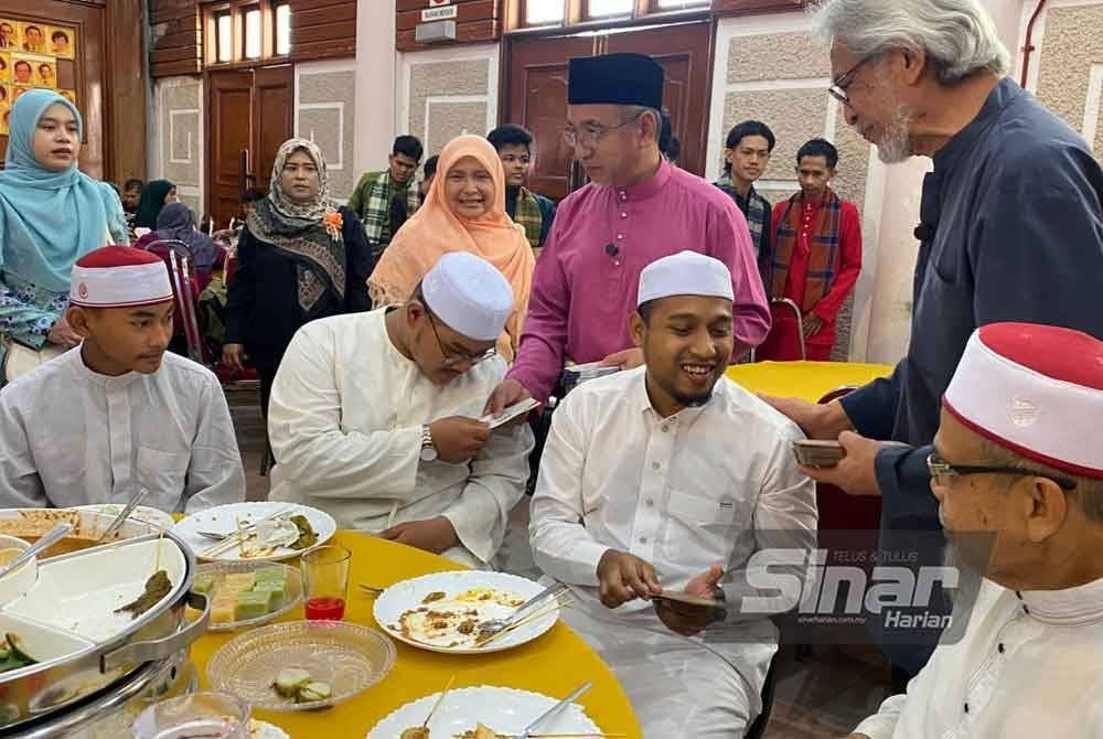Adly (tengah) menyampaikan duit raya kepada tetamu pada Majlis Sambutan Aidilfitri Madani Peringkat DUN Kota Lama di Kota Bharu pada Khamis.