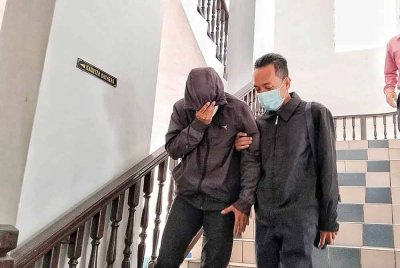 Mohd Rizuan (kiri) ketika dibawa keluar dari Mahkamah Sesyen Melaka pada Khamis.