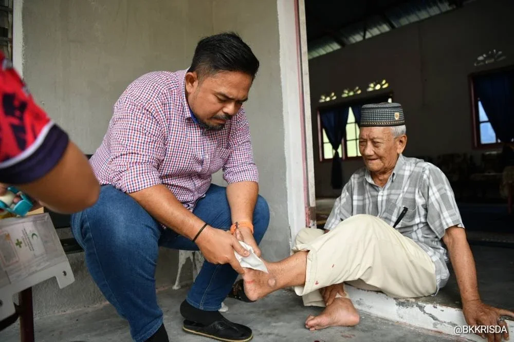 Manndzri membantu pekebun kecil membersihkan luka ketika Program Santunan Pekebun Kecil.