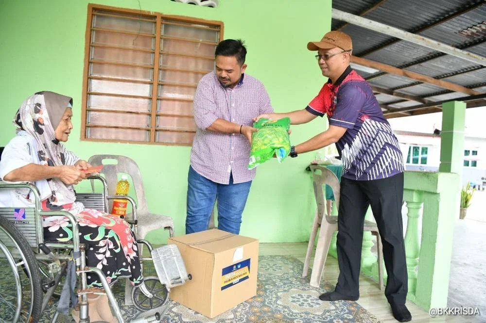 Manndzri (tengah) menyampaikan bantuan keperluan harian kepada pekebun kecil dalam lawatan Program Santunan Pekebun Kecil pada Rabu.