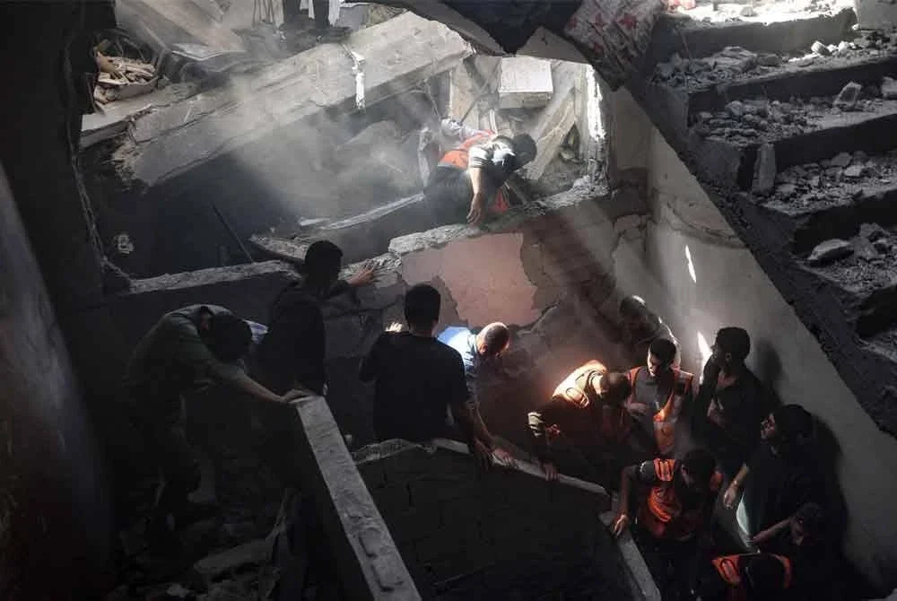 Penduduk dan pasukan penyelamat menuruni tangga sebuah bangunan yang terkena serangan udara Israel di kejiranan timur Shujaiya, Bandar Gaza. Sekurang-kurangnya 1,522 rakyat Palestin terbunuh dalam serangan terbaru Israel. Foto AFP