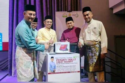 Mohamad (kiri) menunjukkan tablet yang akan disampaikan kepada 263 buah sekolah di negeri ini.