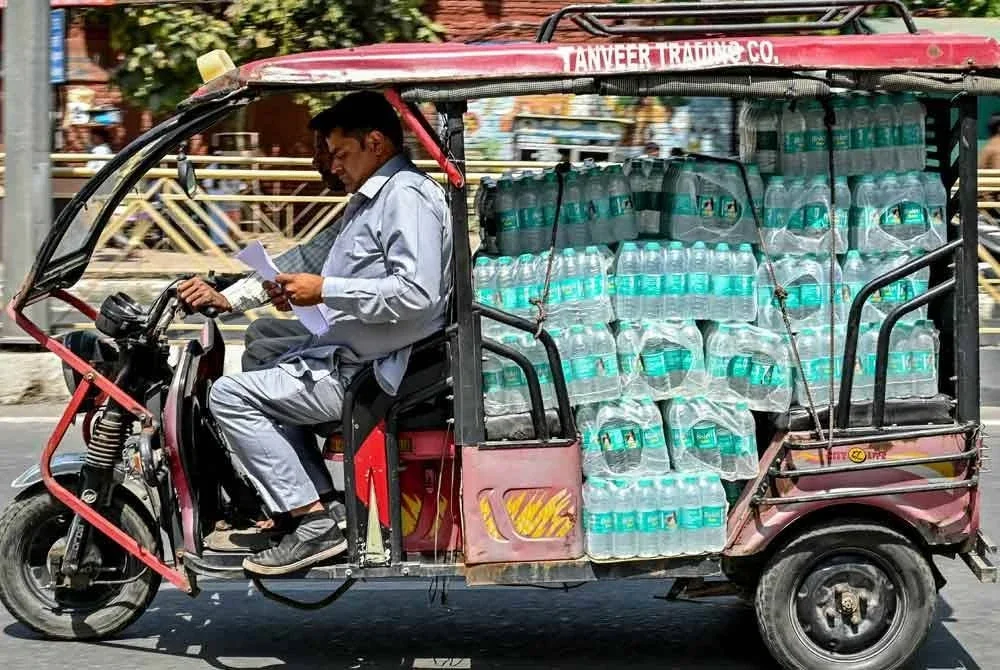 Pemandu beca elektrik membawa berkotak-kotak botol air minuman sebelum diedarkan kepada peruncit.