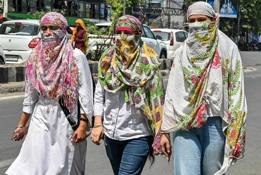 Sekumpulan gadis menutup wajah mereka dengan selendang bagi melindungi diri daripada terik matahari ketika berjalan di sepanjang jalan di Amritsar.