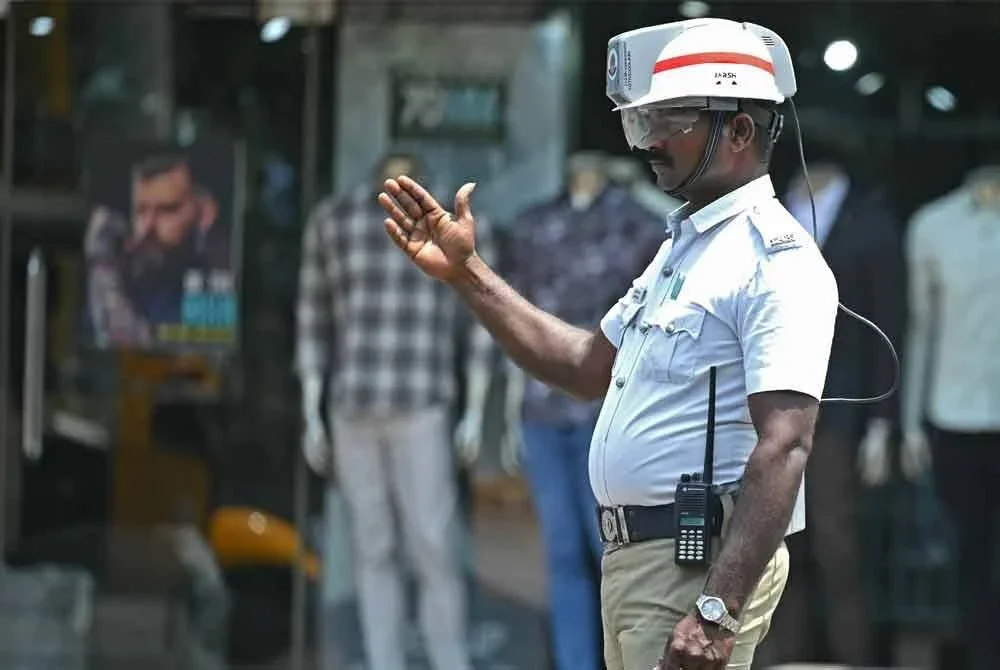 Seorang anggota polis trafik menggunakan topi keledar berhawa dingin bagi mengurangkan bahang panas ketika bertugas di persimpangan jalan dalam cuaca terik di Chennai.