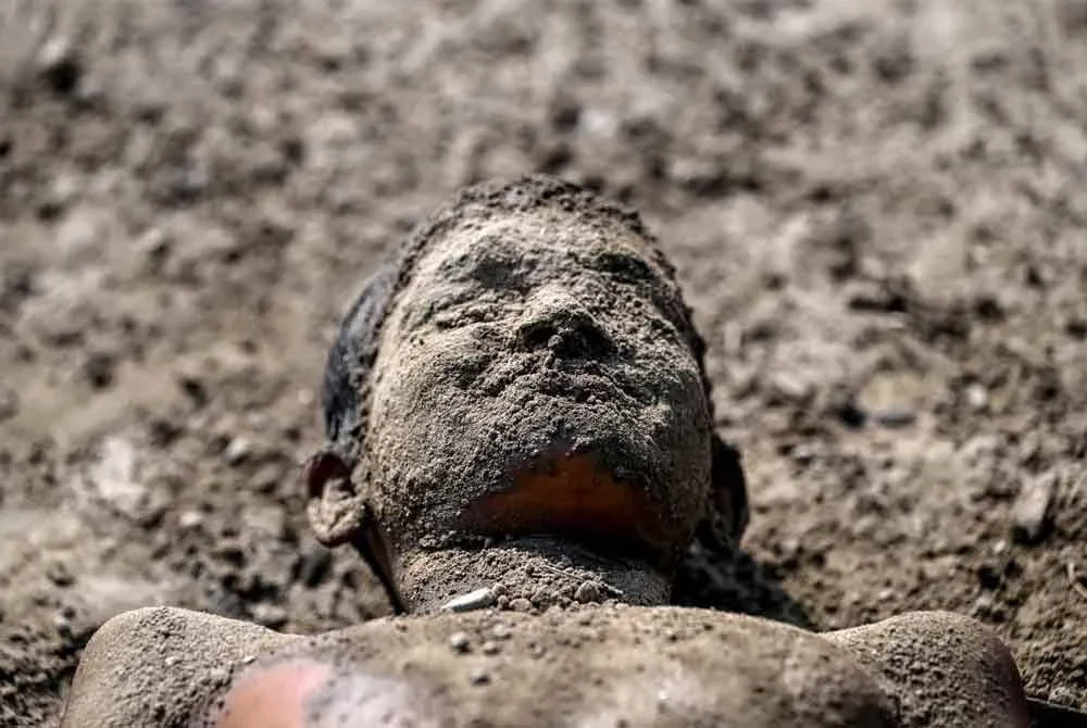 Seorang kanak-kanak lelaki menyapu lumpur ke tubuhnya bagi menyejukkan badan berhampiran tebing Sungai Yamuna ketika cuaca panas terik melanda New Delhi.