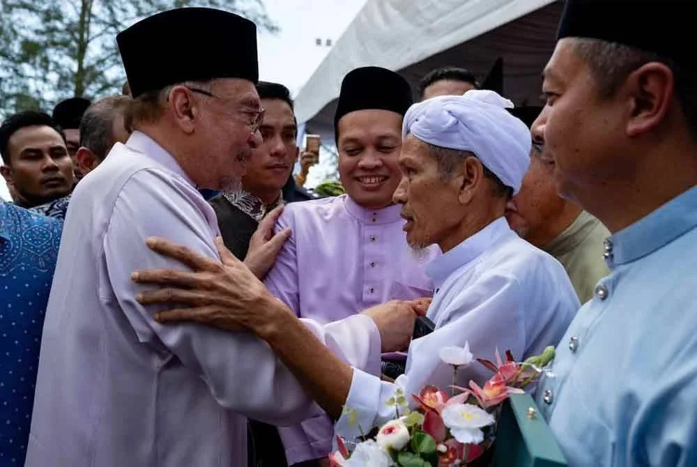 Anwar (kiri) beramah -mesra dengan penduduk yang hadir di Majlis Aidilfitri Madani 2025 Peringkat Negeri Kelantan di Pantai Irama, Bachok pada Sabtu.