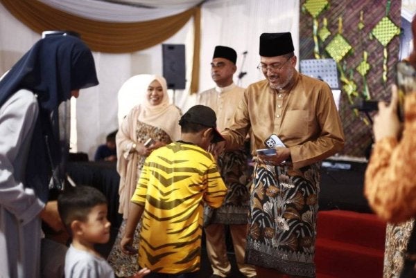 Shaiful Hazizy menyampaikan duit raya kepada kanak-kanak yang hadir Majlis Rumah Terbuka Aidilfitri UMNO Bahagian Merbok, pada Sabtu.