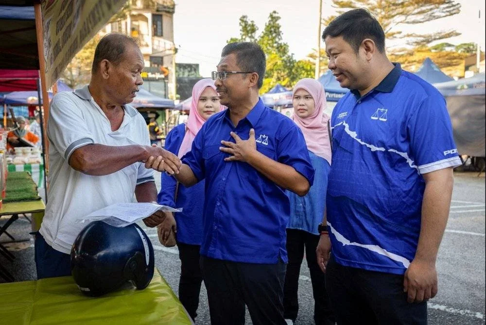 Calon BN, Dr Mohamad Yusri (tengah) beramah mesra bersama penduduk setempat ketika mengadakan tinjauan mesra sempena PRK Ayer Kuning di Pasar Tani Tapah, pada Ahad. Foto Bernama