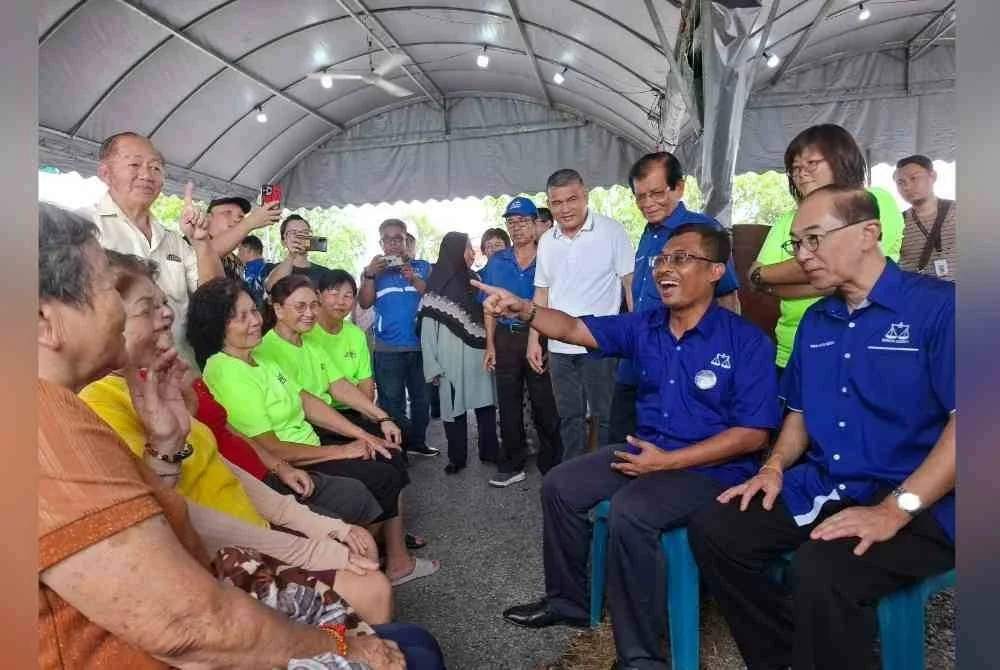 Mohamad Yusri (duduk, dua dari kanan) bersama Hang Soon menyantuni penduduk dan pengundi Kampung Baharu Coldstream di Bidor pada Ahad.