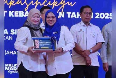 Fadhlina (kiri) menyampaikan cenderahati sebagai tanda penghargaan kepada Timbalan Pengarah Jabatan Pendidikan Negeri Sabah, Indang Kasi Sibin pada pelancaran program Gerakan Massa:#terimakasihcikgu Peringkat Kebangsaan Tahun 2025 di Taiping pada Ahad.