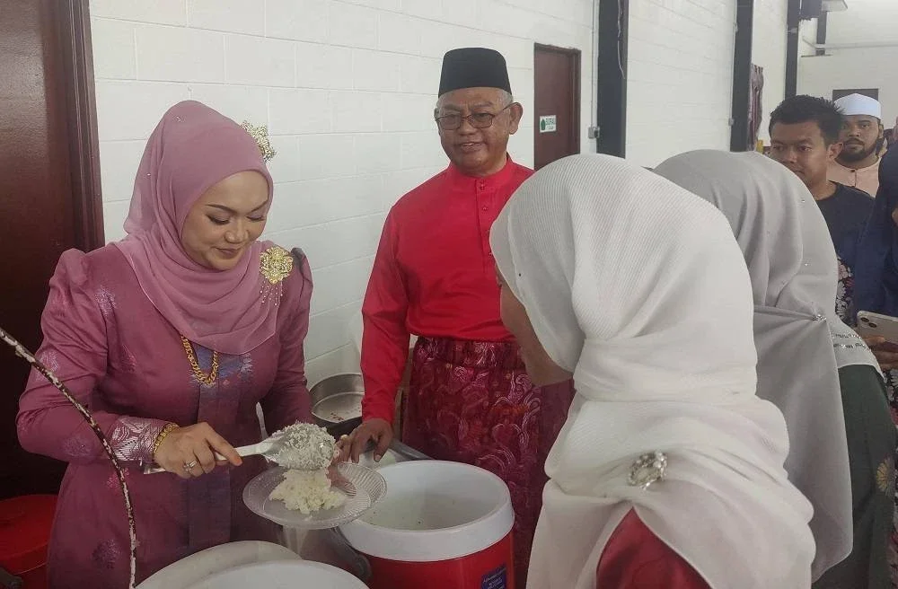 Nurul Syazwani (kiri) melayan tetamu yang hadir pada Rumah Terbuka Aidilfitri di sini pada petang Ahad.