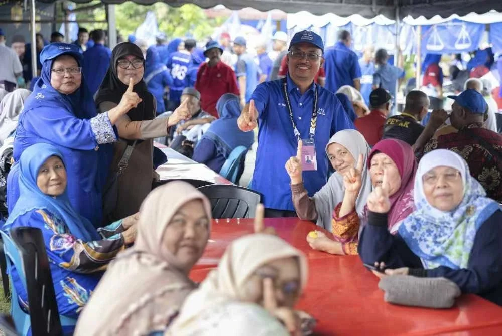 Dr Mohamad Yusri bergambar bersama penduduk setempat pada hari keempat kempen sempena PRK DUN Ayer Kuning di Simpang Tiga pada Selasa. Foto Bernama