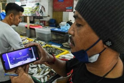 Peniaga ikan, Mohd Rozi Yahaya, 54, turut menyaksikan lintas langsung perjalanan terakhir Tun Abdullah. Foto Bernama
