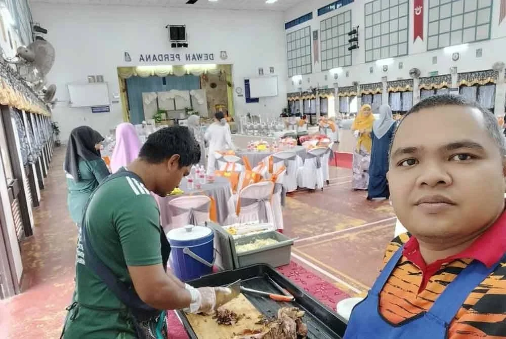 Mohamad (kanan) bersama pembantu menyediakan kambing kukus di satu majlis.