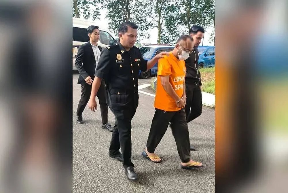 Suspek diiringi pegawai SPRM ketika dibawa ke mahkamah untuk permohonan reman pada Rabu.