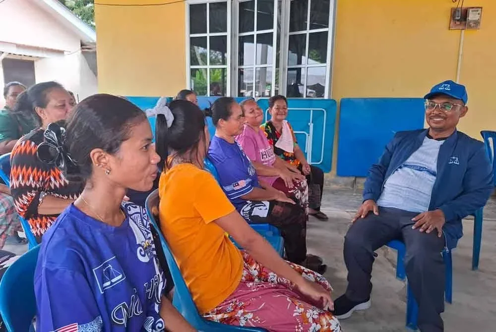 Mohamad Yusri (kanan) menyantuni warga penduduk Kampung Orang Asli Sungai Kurong Dalam sempena kempen PRK DUN Ayer Kuning.