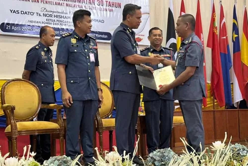 Nor Hisham (tiga dari kiri) menyampaikan Anugerah PerkhidmatanCemerlang kepada pegawai bomba Kelantan.