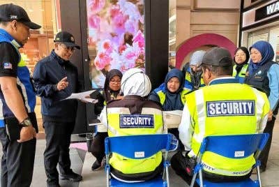 Kamal (dua dari kiri) ketika bertanyakan kepada dua pengawal keselamatan pada Operasi Gaji Minimum JTK di Mahkota Parade, Banda Hilir di sini pada Selasa.