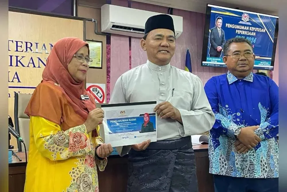 Rahmad (tengah) ketika menunjukkan buku keputusan peperiksaan SPM 2024 selepas sidang akhbar pengumuman keputusan SPM Melaka 2024 di Jabatan Pendidikan Negeri Melaka di Bukit Beruang pada Khamis.