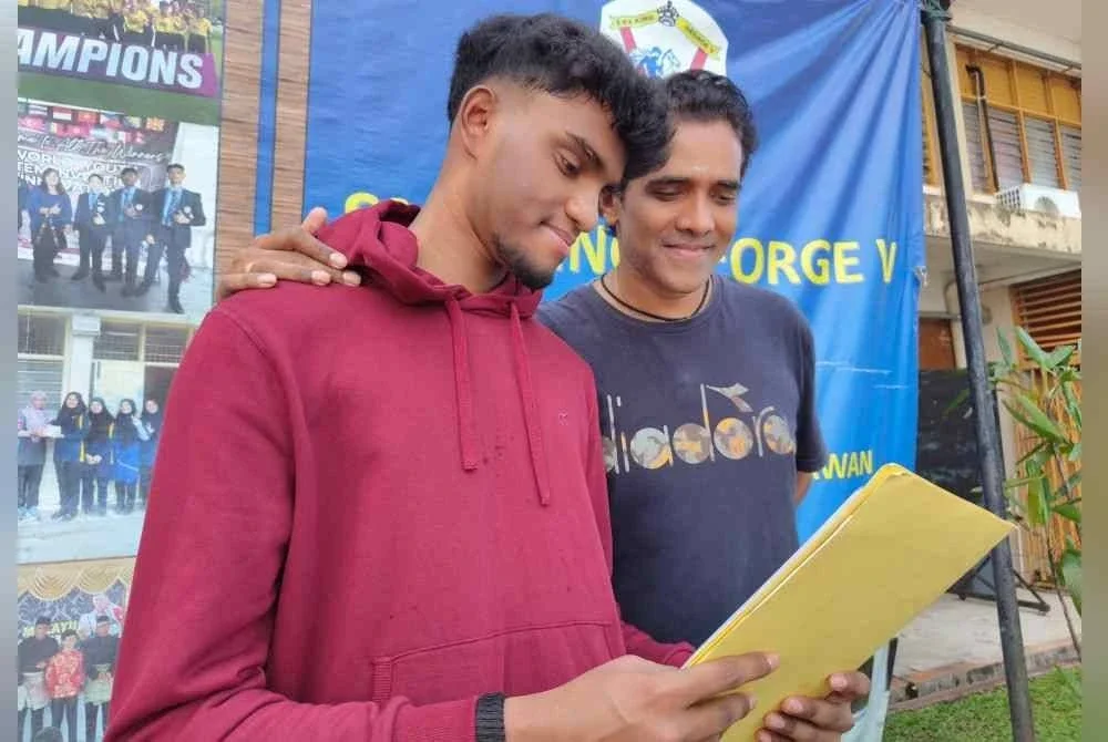 Pravieen (kiri) menunjukkan keputusan SPM kepada bapanya, B Ravindran di SMK King George V, Seremban.
