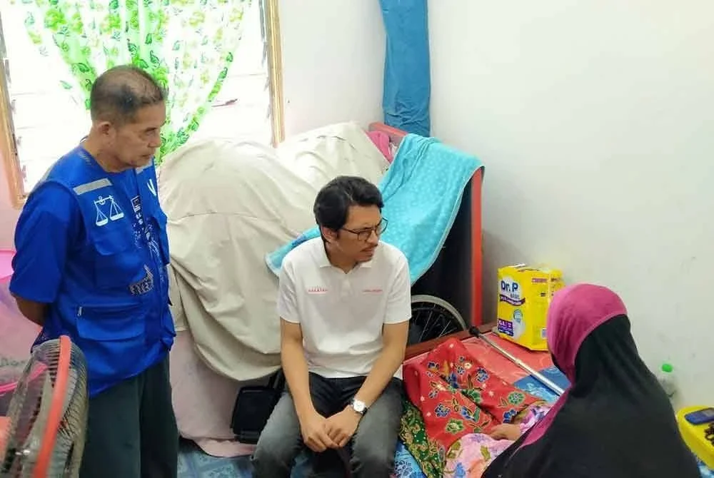 Muhammad Kamil (tengah) melawat seorang penduduk ketika program Ziarah Kasih Madani di Kampung Tanah Pinggir pada Khamis.