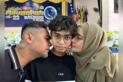 Sufian (kiri) dan Wan Faziawati mencuim Aimimuqri Harraz yang memperoleh keputusan cemerlang dalam SPM 2024.