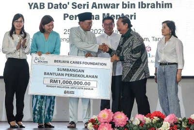 Anwar menerima sumbangan bantuan persekolahan daripada Berjaya Cares Foundation yang disampaikan oleh Pengasas Berjaya Corporation Bhd (BCorp) Tan Sri Vincent Tan Chee Yioun (dua, kanan) pada Majlis Santuni Kasih bersama Pelajar-pelajar Parlimen Tambun di Ipoh pada Jumaat. Foto Bernama