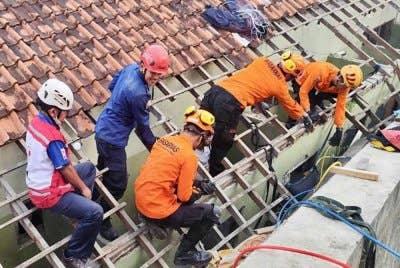 Pasukan penyelamat berusaha mengeluarkan mangsa yang dihempap dinding tangki air di sekolah berkenaan.
