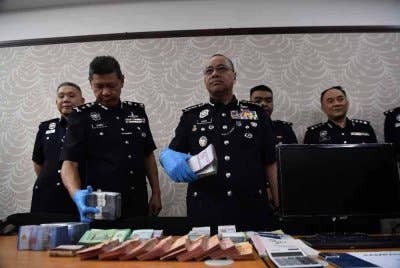 Noor Hisam (tengah) menunjukkan wang tunai yang dirampas daripada ejen sindiket perjudian loteri awam di Ipoh.