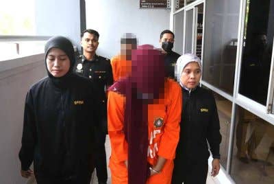 Penolong jurutera dan suaminya diiring pegawai SPRM ketika hadir ke mahkamah bagi permohonan reman.