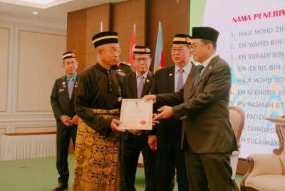 Mohamed Khaled (kanan) menyampaikan sijil pada Persidangan Perwakilan PVATM kali ke-56 di Tiram pada Khamis.