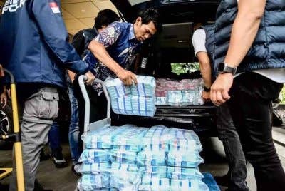 Anggota polis memunggah timbunan wang kertas rupiah dari sebuah kereta di ibu pejabat Polis Negara di Jakarta - Foto: Antara